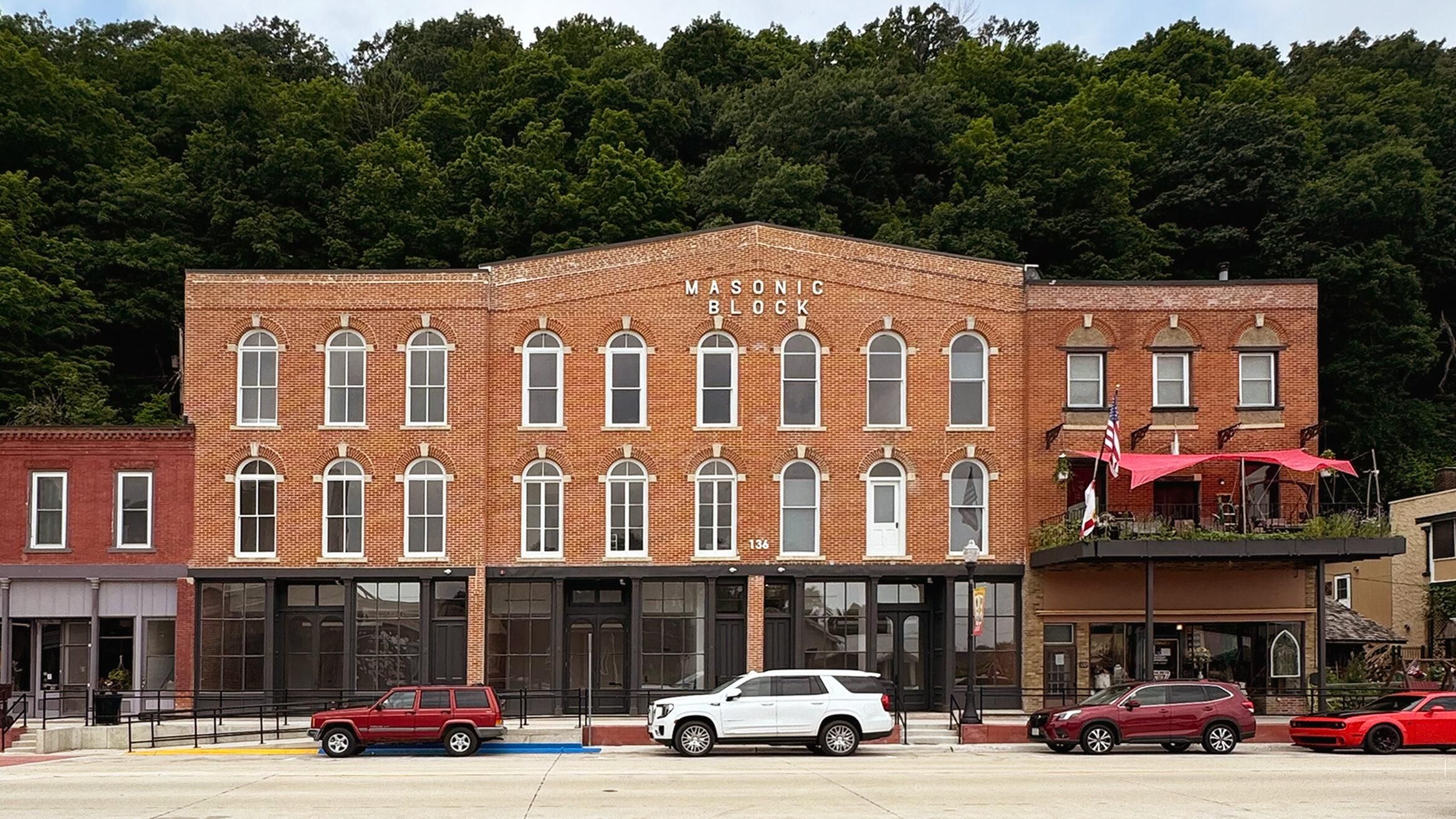 The restored brick Masonic Block on Main Street in McGregor, Iowa, with wooded bluffs behind